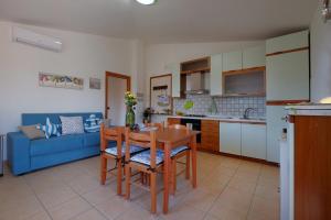 eine Küche und ein Wohnzimmer mit einem Tisch und einem blauen Sofa in der Unterkunft Casa "Maestrale " in Porto Pino