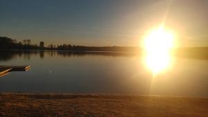 a large lake with the sun setting on the water at Domek w Borach in Nowe