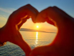 a heart shaped photo of a sunset on the beach at LOVELY APARTMENTS Senj - Spectacular Sea View & Free Parking & WI-FI in Senj