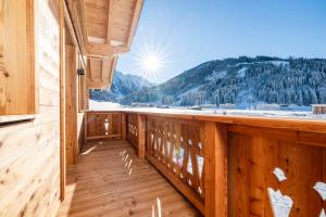 a wooden balcony with a view of the snow covered mountains at BEIM LOIS Dorfblick - AlpenLuxus Collection in Gerlos