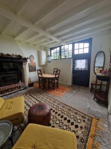 a living room with a table and chairs and a fireplace at Chaumière historique à 5min de la plage in Veules-les-Roses