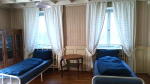 ein Zimmer mit zwei Betten und einem Tisch und zwei Fenstern in der Unterkunft Charmant gîte vosgien avec 9 chambres pour 22 personnes in Fellering