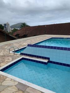 a large swimming pool with blue tiles on it at Apartment in Prainha Caraguá in Caraguatatuba