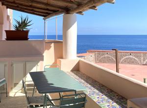 a table and chairs on a balcony with the ocean at Casa Cappero - sul porto di Malfa in Malfa