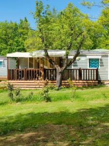 a house with a porch with a tree at Camping du Moulin de Thoard in Thoard