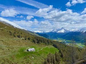 uma casa no lado de uma colina com montanhas em Alp Es-Cha Dadour em Madulain
