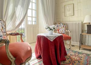 a living room with a table with a vase of flowers on it at LE PRESBYTÈRE DE LA CITE ROYALE DE LOCHES in Loches