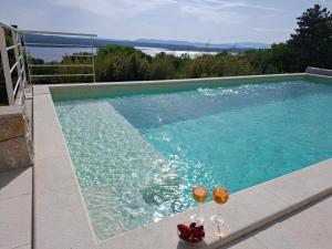 a swimming pool with two glasses of wine at Villa Belvedere in Crikvenica