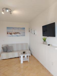 a white living room with a white couch and a tv at Apartments Gojevic in Bol +41 photos