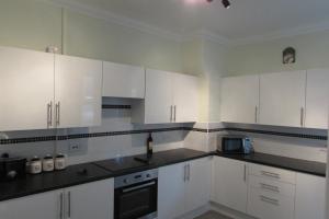 a kitchen with white cabinets and black counter tops at Idyllic Bexhill centre flat above pub in Bexhill