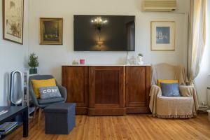 a living room with two chairs and a tv on a wall at Liston Suites Anastasia in Corfu