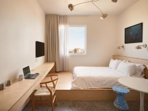 a bedroom with a bed and a desk with a laptop at Petit hôtel de la Montagne in Havre-Aubert