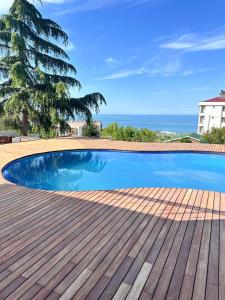 a swimming pool on a wooden deck with the ocean in the background at Trabzon House - Pool, Sea View & Nature in Bostancı