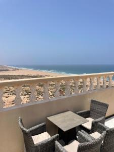 a table and chairs on a balcony overlooking the beach at Warm apartment with sea view in Rbat