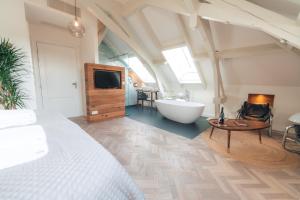 a bedroom with a bed and a tub and a television at Boutique Hotel De Witte Dame in Abcoude