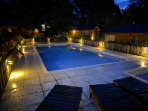 a swimming pool with lights in a backyard at night at Cabañas Boutique Los Cipreses in Villa Ventana