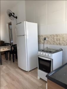 a kitchen with a white refrigerator and a stove at Aconchego Jardim Ipê proximo ao Paraguai in Foz do Iguaçu