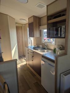 a kitchen with a sink and a counter top at Abi Sunset - Camber Sands in Camber +6 photos