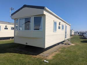 a small white trailer parked in a yard at Abi Sunset - Camber Sands in Camber