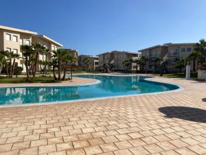 a swimming pool in a resort with trees and buildings at APPARTEMENT BORDURE PLAGE in Kenitra