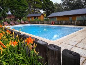 a swimming pool in a yard with flowers at Cabañas Boutique Los Cipreses in Villa Ventana