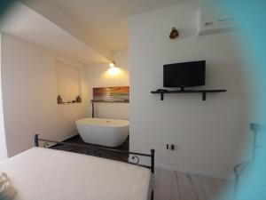a bedroom with a tub and a tv on the wall at La Piccola Corte da Anita in Tortolì