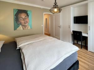 a bedroom with a bed with a painting on the wall at Louise Boutique Apartment 2 - Stilvolles Apartment im Herzen Friedrichshafens in Friedrichshafen