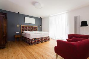 a bedroom with a bed and a red chair at KIRCHENWIRT an der Weinstrasse - Boutique Hotel in Ehrenhausen