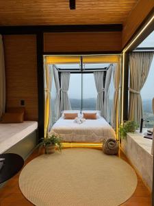 a bedroom with a bed with a large window at Cabanas Duas Faces - Urubici in Urubici