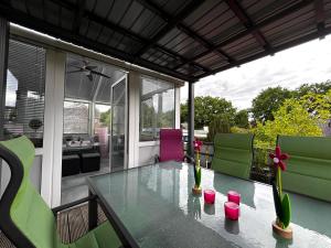 a glass table on a patio with green and pink chairs at Ferienwohnung Micaela in Haselünne