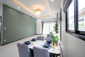 a dining room with a white table and chairs at นงนุช วิลเลจ&พลูวิลล่า in Ban Nong Bua