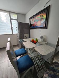 a dining room with a glass table and blue chairs at Apartamento Portal el Dorado, a solo 5 min del aeropuerto, vias, cll 26 in Bogotá