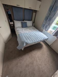 a small bedroom with a bed with a blue headboard at Hesket Caravan Park PLOT 42 3 pm check in Can sleep 6 with bed settee No commercial vans allowed in Carlisle