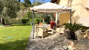 a patio with an umbrella and chairs and a yard at Giardino sul Fiume, Oasi di Relax con Vista e Parcheggio Privato a 10 min dal centro in Ascoli Piceno