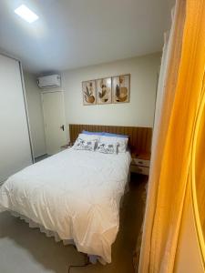 een slaapkamer met een wit bed en een geel gordijn bij Maragogi-Peroba Ville Residence03 in Maragogi