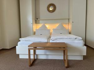 a bed with white pillows and a table on it at Hotelpension Sanders Höft - Direkt am Strandaufgang in Juist