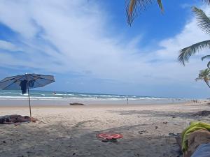 a beach with an umbrella on the sand and the ocean at Apartamento Próximo a Pituba in Itacaré