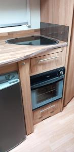 a kitchen with a stove and a counter top at Cosy Caravan in Scenic Snowdonia in Cwm-y-glo