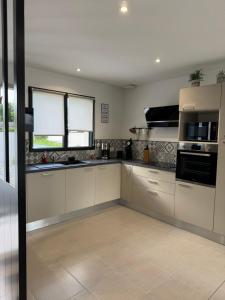 a large kitchen with white cabinets and a window at L'Olivier de munet in Distré