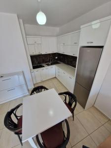 a kitchen with a white table and chairs and a refrigerator at Summer Apartments in Shengjin in Shëngjin