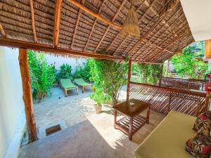 an open patio with a table and a straw roof at Ananda Beach Hotel in Paje