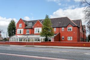 una gran casa de ladrillo rojo al lado de una calle en Trivelles Mayfair,stockport, en Mánchester