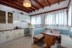 a kitchen with white cabinets and a wooden table at Villa with Piano by Chania Living Stories in Chania Town