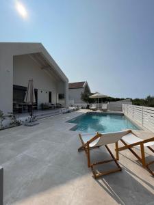 a swimming pool with two lounge chairs next to a building at Myrtia Villas I in Anomeriá