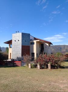 a building with a fence in front of a field at La Macarena Suites in Villa General Belgrano