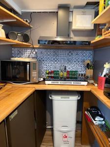 a kitchen with a counter with a microwave and a trash can at Gîte Le Sambre in Thuin