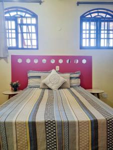 Cama grande en habitación con 2 ventanas en Casa encantadora 900m da PRAIA de Itaipuaçu, en Maricá