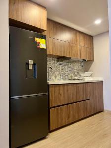 a kitchen with a black refrigerator and wooden cabinets at Torre ventto Loft Amanecer en las nubes de Bogotá in Bogotá