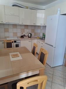 a kitchen with a table and a white refrigerator at Apartman MAGNIFICO in Donje Mladice