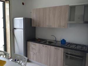 サン・ピエトロ・イン・ベヴァーニャにあるCasa Accesso Spiaggiaの木製のキャビネットと白い冷蔵庫を備えたキッチン